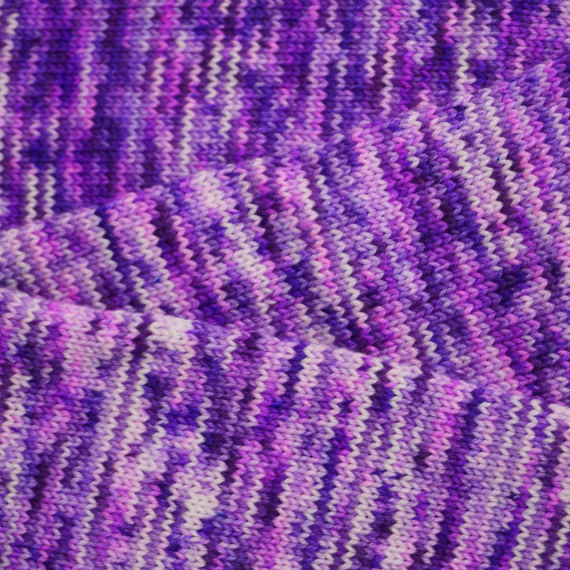 Hand-dyed yarn knit swatch in shades of purple, lavender, and soft pink