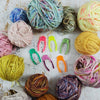 Acrylic skein locks in bright colors surrounded by balls of hand-dyed yarn