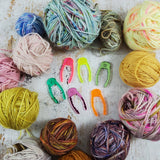 Acrylic skein locks in bright colors surrounded by balls of hand-dyed yarn
