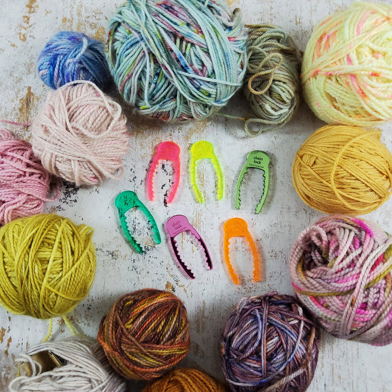 Acrylic skein locks in bright colors surrounded by balls of hand-dyed yarn