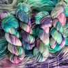 Hand-dyed yarn skeins featuring green, teal, purple, and pink color variations, displayed side by side on a gray wood background with Yarnable labels visible.