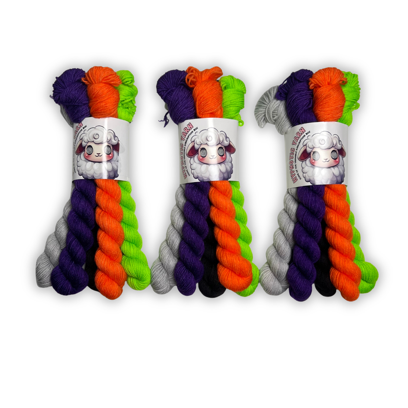 Three October 2026 Staff Pick fingering mini sets standing side by side in purple, orange, lime green, black and light gray