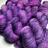 Close-up of bright purple and pink Zodiac Sagittarius yarn skeins with deep green speckles
