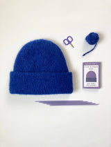 Blue folded brim knit hat beside the Flip-N-Fold Hat mini zine