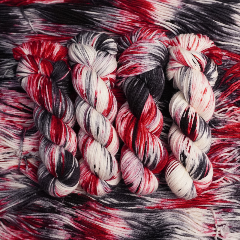 Bundles of red, black, and white yarn on a textured red and black background