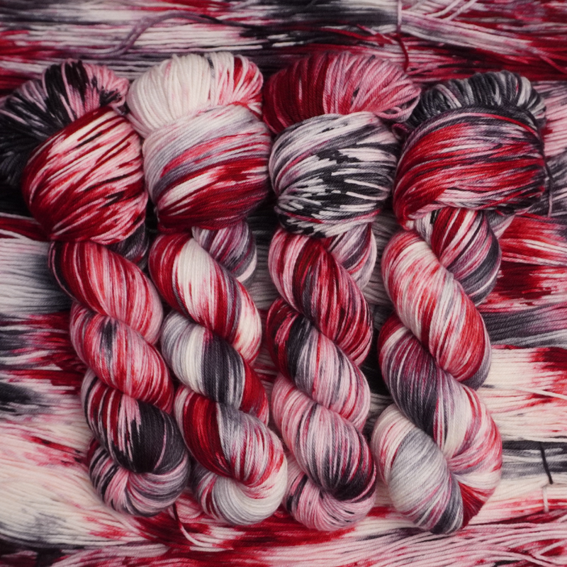 Close-up of multicolored yarn skeins with red, black, and white patterns.