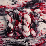 Close-up of multicolored yarn skeins with red, black, and white patterns.