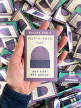 Flip-N-Fold Hat mini zine held in hand, printed with Recipe for a Flip-N-Fold Hat