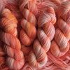 Multiple hand-dyed yarn skeins in warm pink, peach, and creamy yellow shades, displayed side by side with Yarnable by Hypnotic Yarn branding visible.