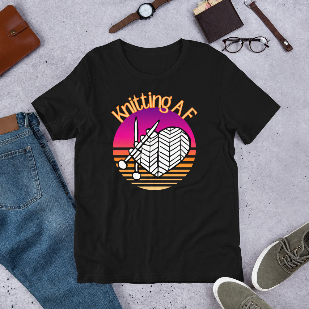 Black scoop neck tee with the Knitting AF design in magenta and orange sunset stripes with knitting needles