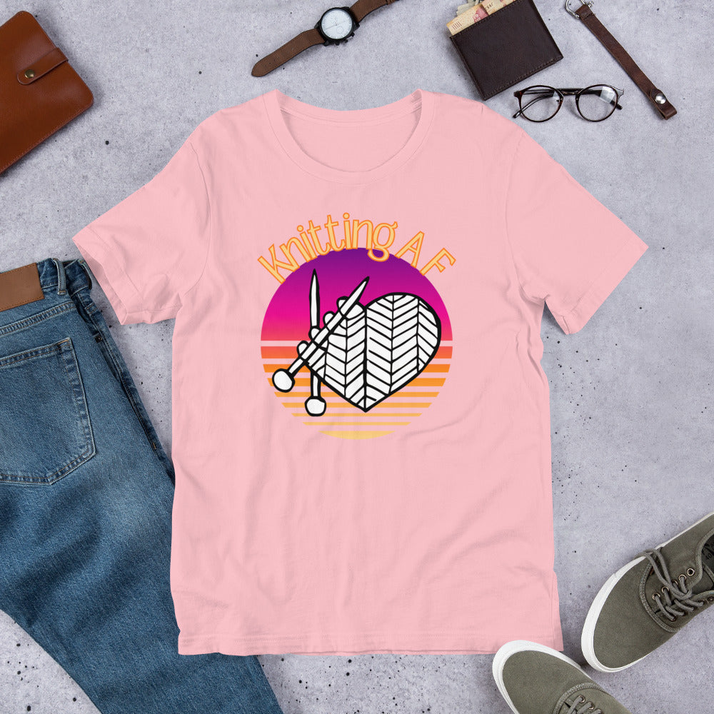 Pink scoop neck tee with the Knitting AF design in magenta and orange sunset stripes with knitting needles