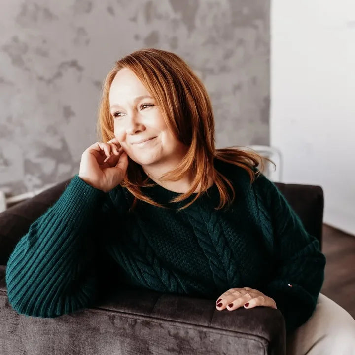 Cheryl, founder of Hypnotic Yarn, smiling in a green cable-knit sweater